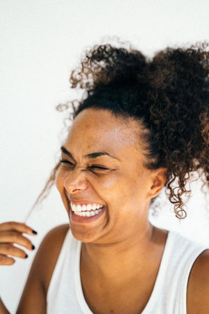 laughing woman with curly ponytail - benefits of cupuacu butter for natural hair
